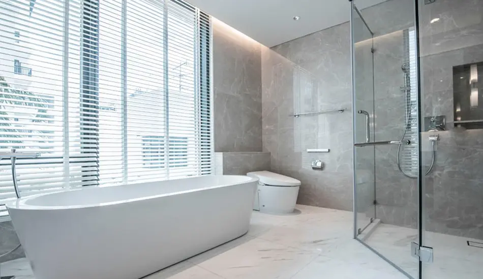 Baño remodelado con tina, ducha en vidrio templado y enchape claro