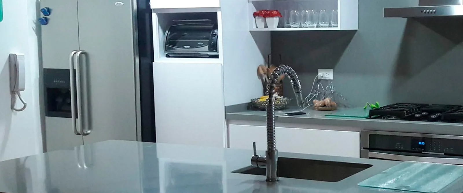 Cocina moderna remodelada con mesón en acero y gabinetes blancos